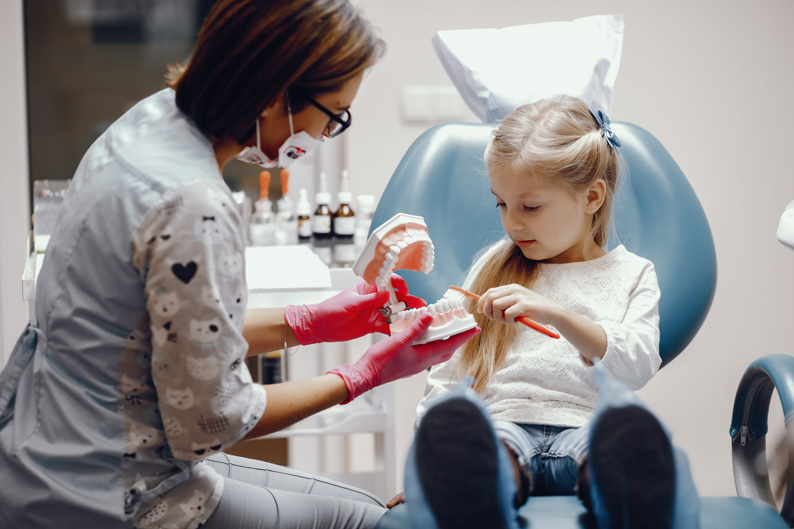 Little girl talking to the dendist. Child in the dentist's office. Woman in a uniform